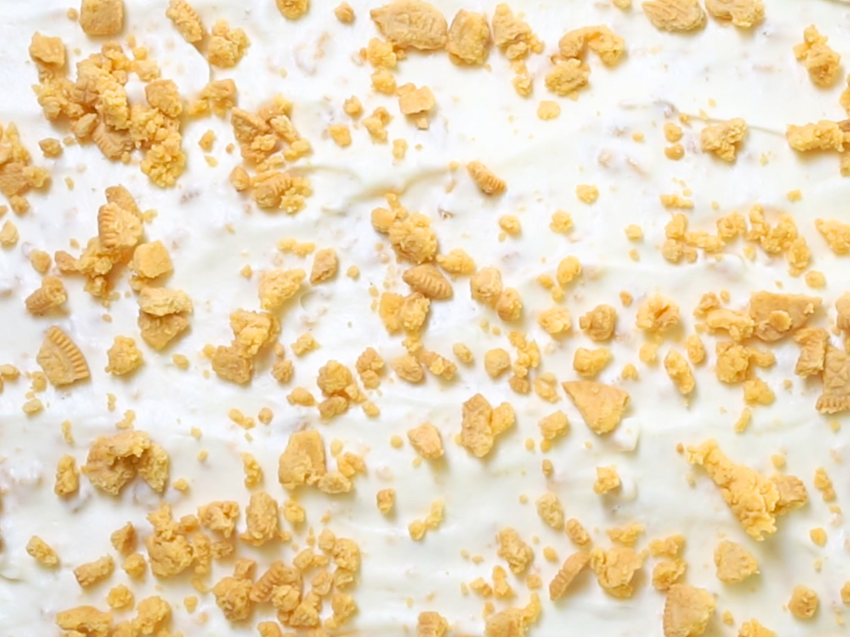 Top down view of a cake covered with whipped cream and crushed cookies - Hostess At Heart