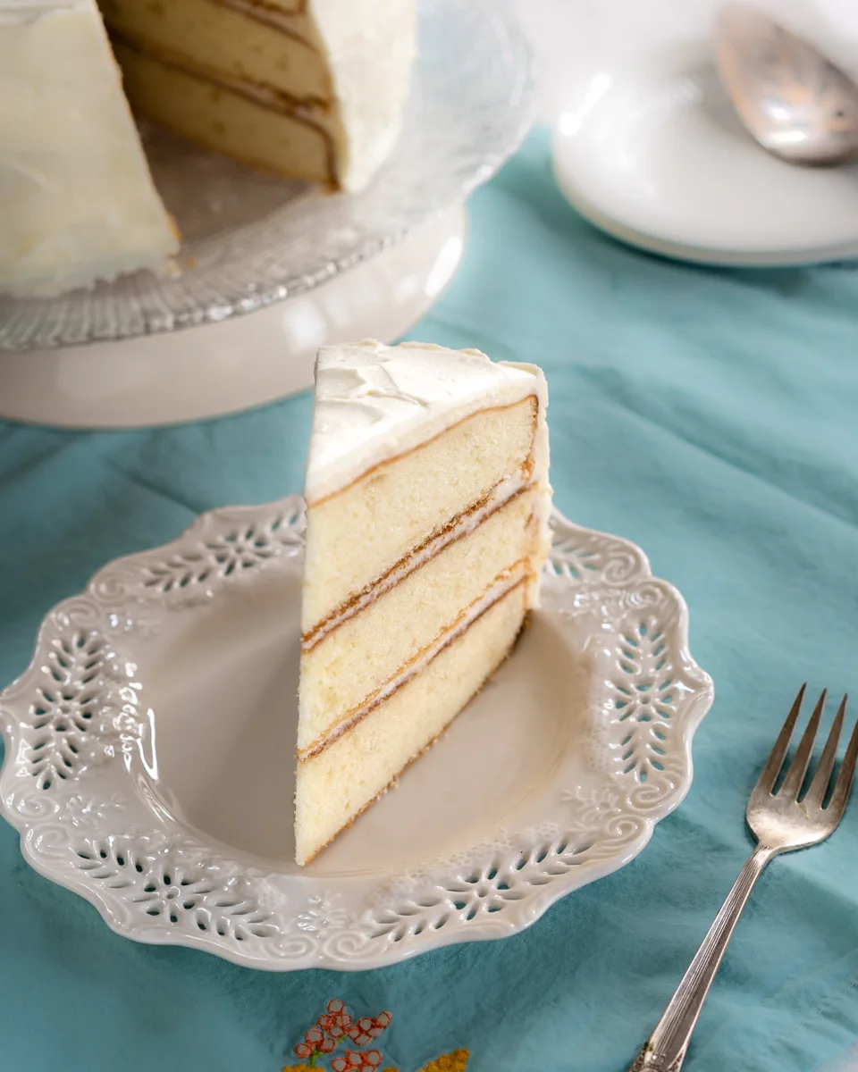 Front view of a slice of a three-layer Vanilla Cake baked from scratch - Hostess At Heart
