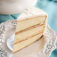Sideview of a slice of homemade layer cake with white frosting. Hostess At Heart