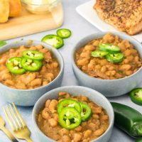 Angled view of a bowl of cooked beans topped with slices of jalapenos - Hostess At Heart