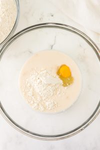 A glass bowl with flour, evaporated milk, and an egg mixed together - Hostess At Heart