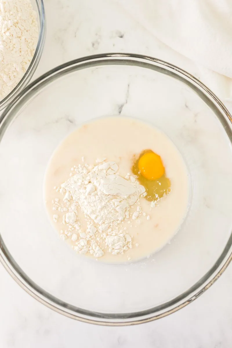 A glass bowl with flour, evaporated milk, and an egg mixed together - Hostess At Heart