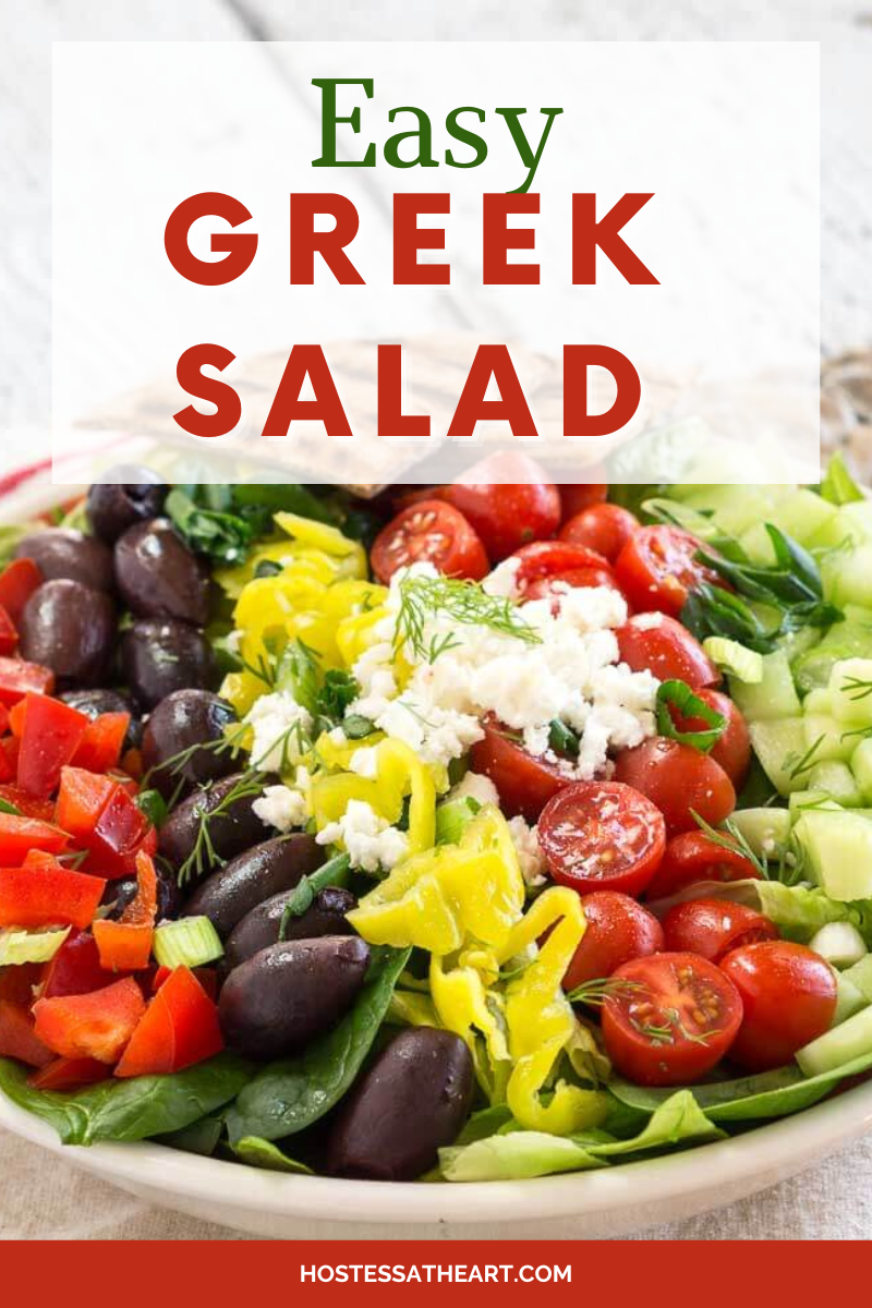 Close-up view of a Mediterranean salad topped with olives, tomatoes, cucumbers, tomatoes, and banana peppers. Hostess At Heart