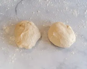 Bread dough split in half on a floured surface - Hostess At Heart