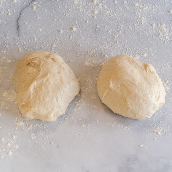 Bread dough split in half on a floured surface - Hostess At Heart