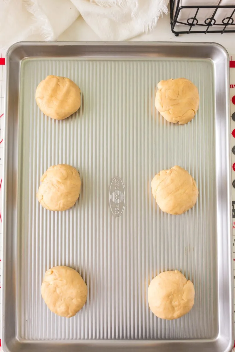 Concha dough rolled into balls and flattened sitting on a baking sheet. Hostess At Heart