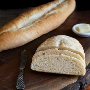 Angled view of a Cuban baguette with two slices leaning on the loaf. Hostess At Heart