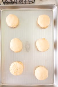Mexican Sweet Bread dough rolled into balls and topped with vanilla topping on a baking sheet.