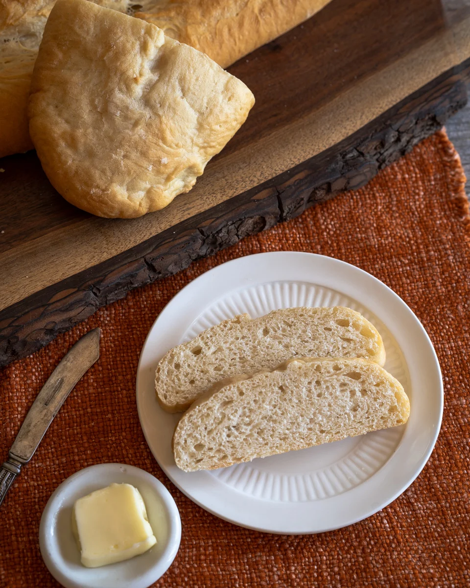 Top-down view of two slices of Pan Cubano bread wit the loaf in the background. - Hostess At Heart