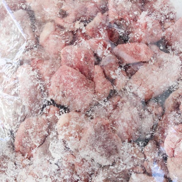 Raw cubes of beef combined with cornstarch and spices in a ziplock bag. Hostess At Heart
