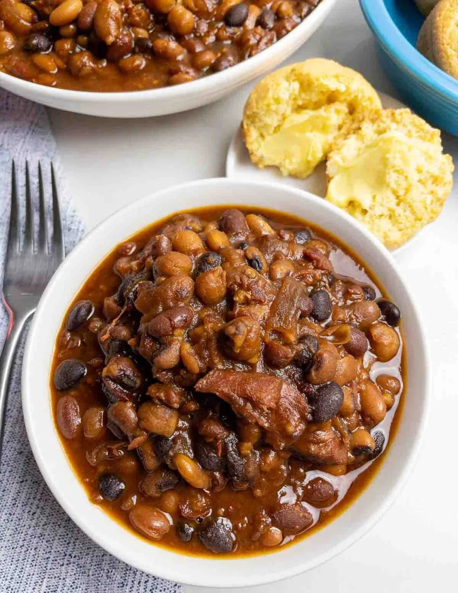 Top down view of a bowl of baked beans containing pieces of ham.