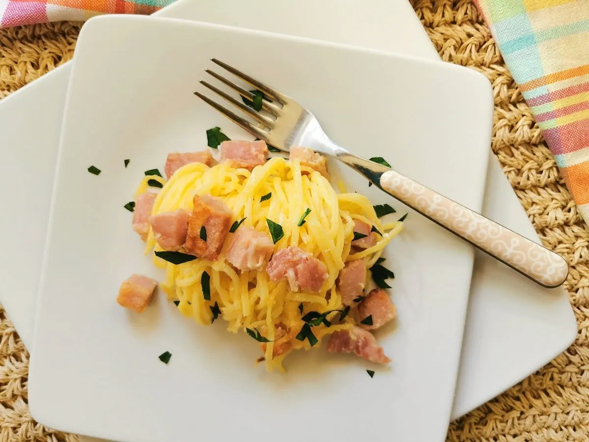 Top down view of a plate holding pasta and diced ham.