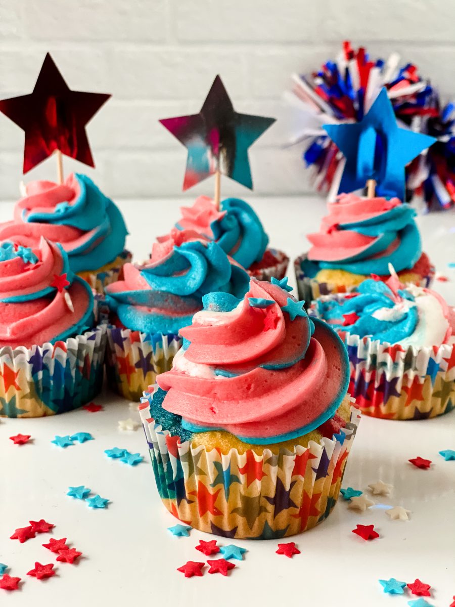 Sideview of cupcakes in star cupcake liners topped with colored swirled frosting and star sprinkles - Hostess At Heart