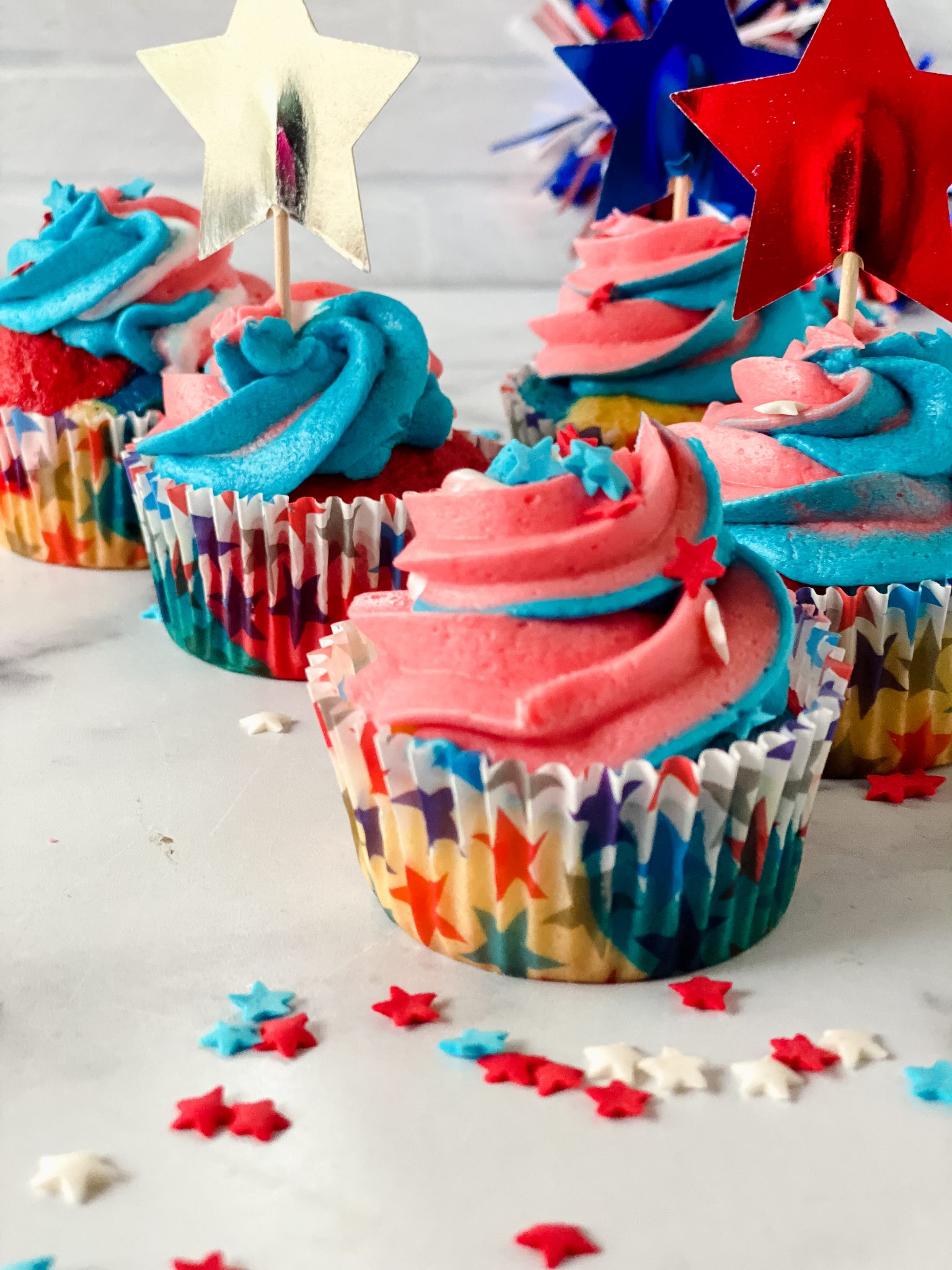 Sideview of Independence Day red, white, and blue cupcakes with swirled frosting and colored star sprinkles - Hostess At Heart