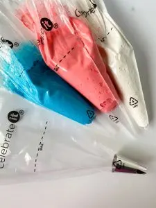 3 pastry bags filled with red, white, and blue frosting next to one empty bag with a tip. Hostess At Heart