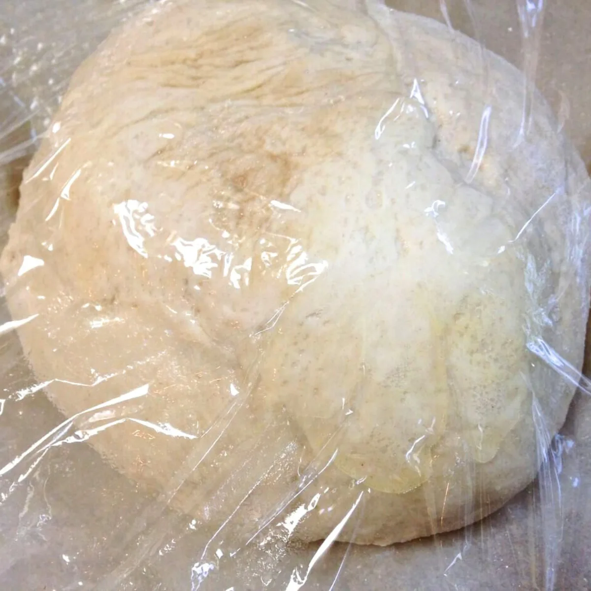 A ball of bread dough covered with plastic wrap