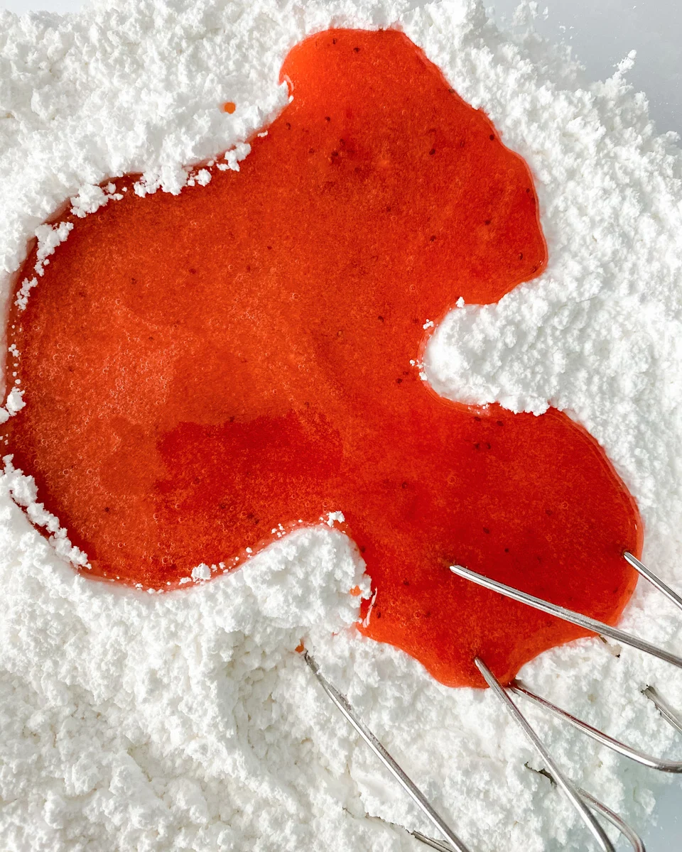 Powdered sugar with a pool of fresh strawberry puree added. Hostess At Heart