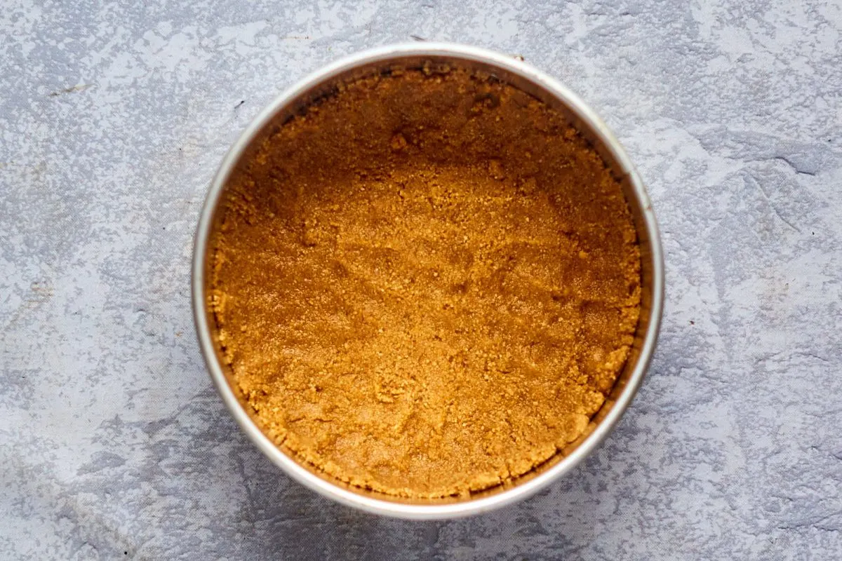 Pressed Graham Cracker crumbs in the bottom of a spring form pan.