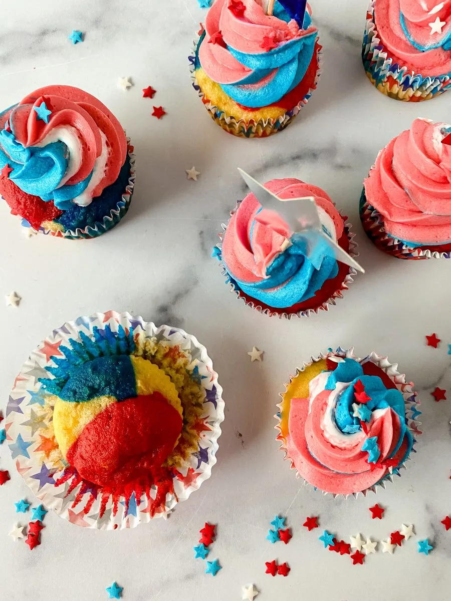 Top-down view of cupcakes with swirled red, white, and blue frosting and patriotic star sprinkles - Hostess At Heart