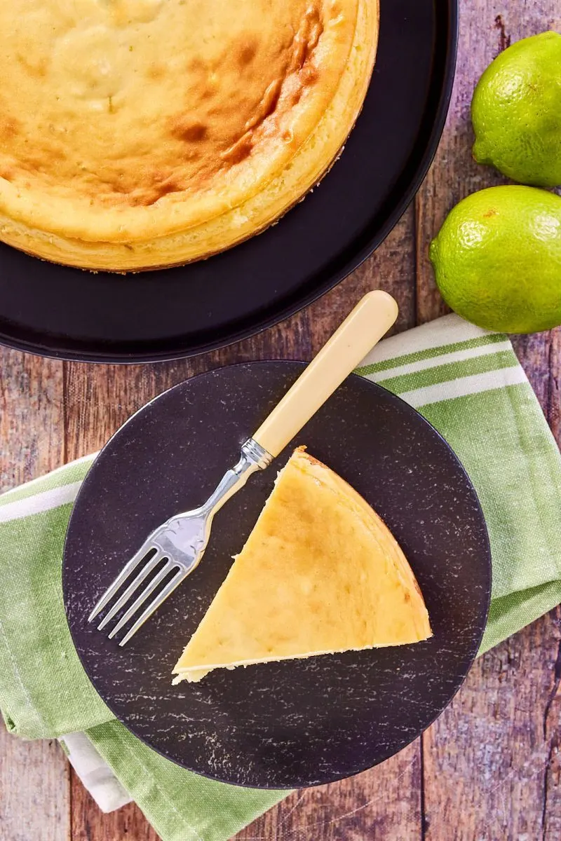 Top down view of a slice of lime cheesecake on a plate with the lime pie cheesecake in the back - Hostess At Heart