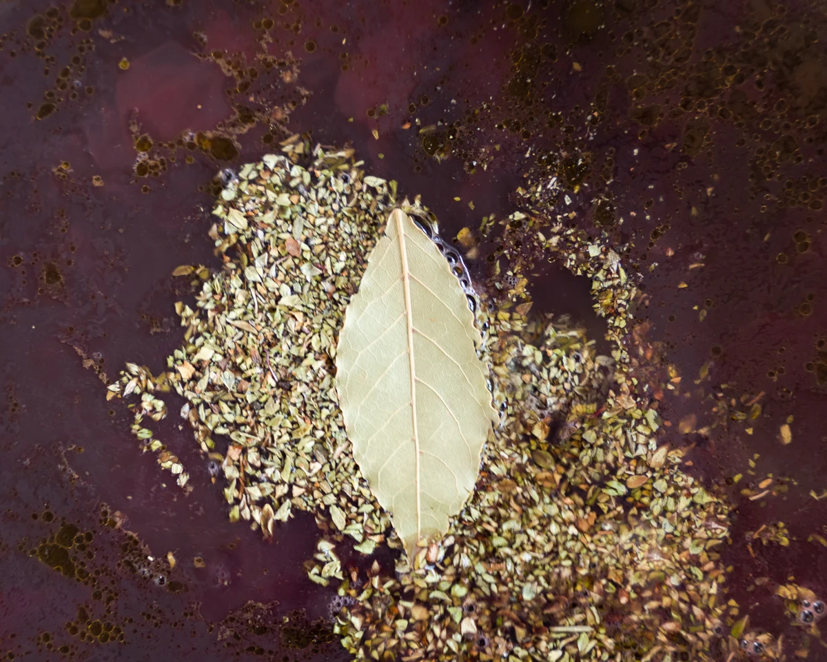 Spices and a bay leaf sitting on top of a pot of cooking black beans. - Hostess At Heart