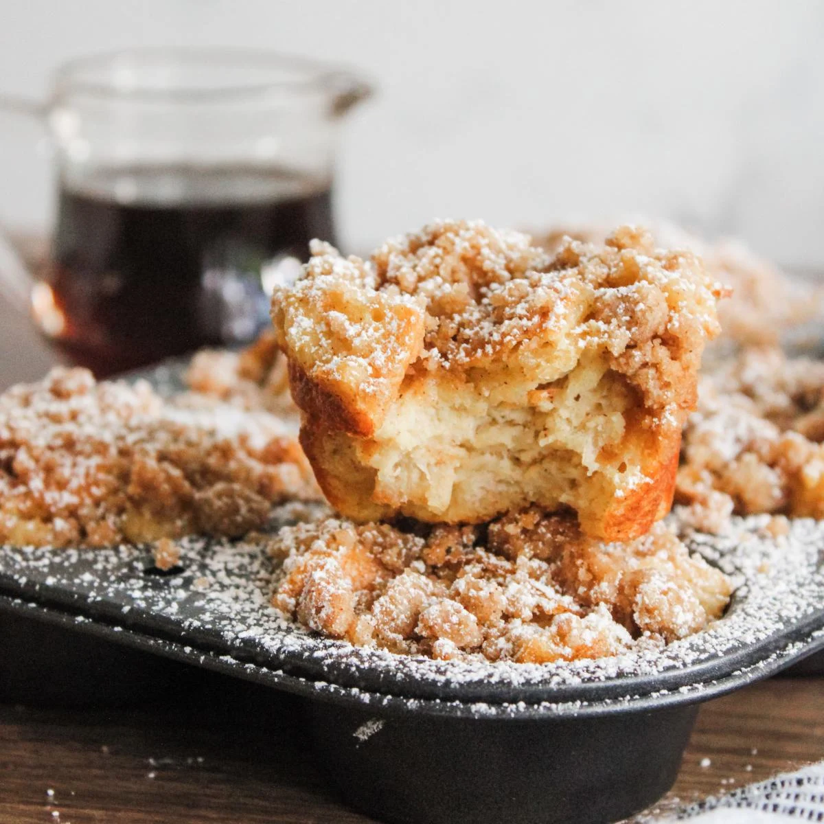 Front view of a muffin tin filled with French Toast Muffins dusted with powdered sugar. Hostess At Heart