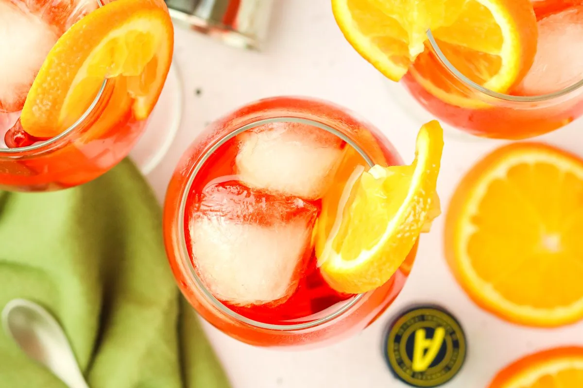 Top down view of glasses of aperol spritz cocktail garnished with orange slices - Hostess At Heart