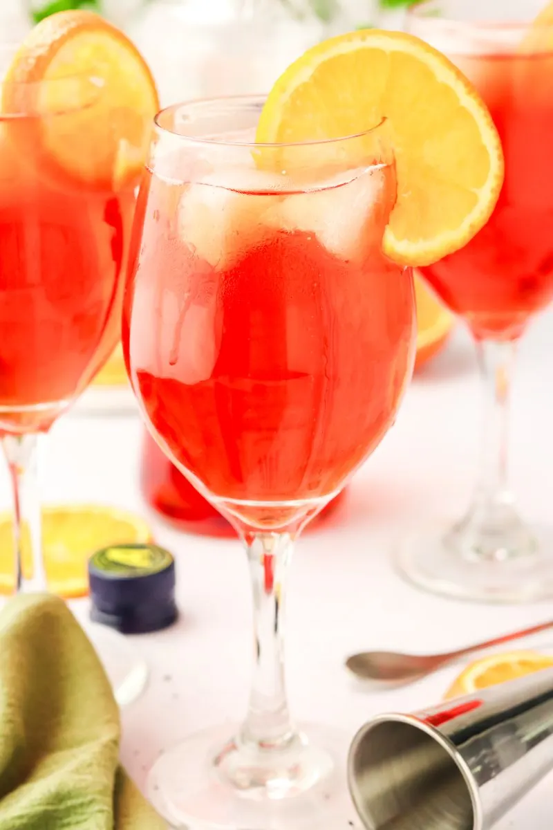 Sideview of three Aperol cocktails in a triangle shape and garnished with a orange wheel. Hostess At Heart