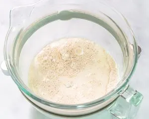 Top down view of a mixing bowl filled with the ingredients to make bread dough - Hostess At Heart