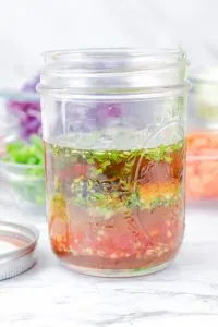A sideview of a jar filled with Thai Vinaigrette ingredients - Hostess At Heart