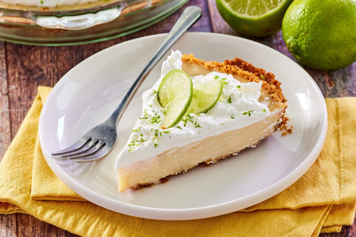 Angled view of a slice of creamy pie zested and garnished with fresh lime. Hostess At Heart