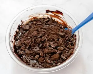Crushed Oreos being folded into a chocolate batter - Hostess At Heart