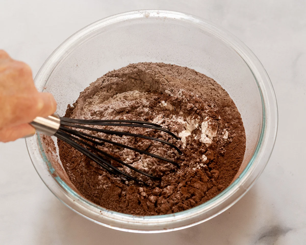 A mixing bowl with flour and cocoa being whisked together - Hostess At Heart