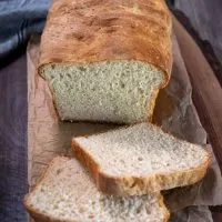 Front view of a loaf of homemade bread with the first to slices cut and laying in the front - Hostess At Heart
