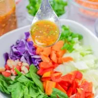 A spoon of Thai Dressing hovering over a bowl of Thai Salad - Hostess At Heart