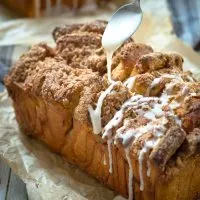 A loaf of Apple pull apart bread covered in streusel and dripping with glaze. Hostess At Heart