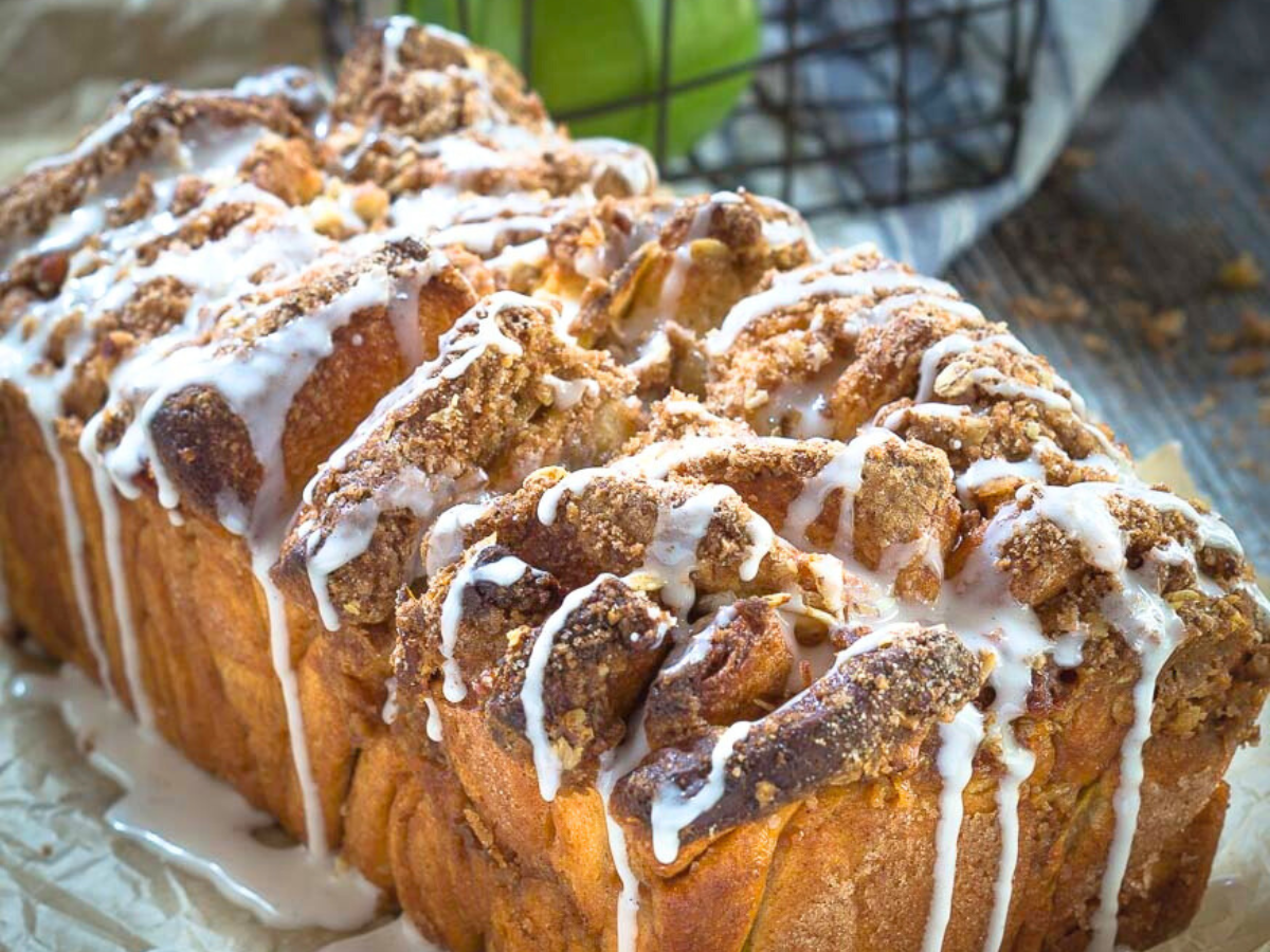 Angled view of a loaf of pull-apart bread topped with streusel and a sugar glaze dripping down the sides - Hostess At Heart