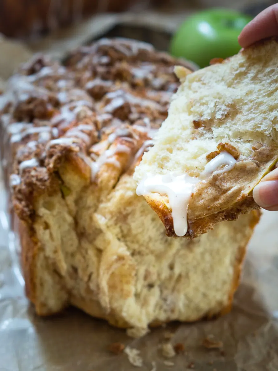 Front view of a piece of apple cinnamon pull apart bread dripping with glaze - Hostess At Heart