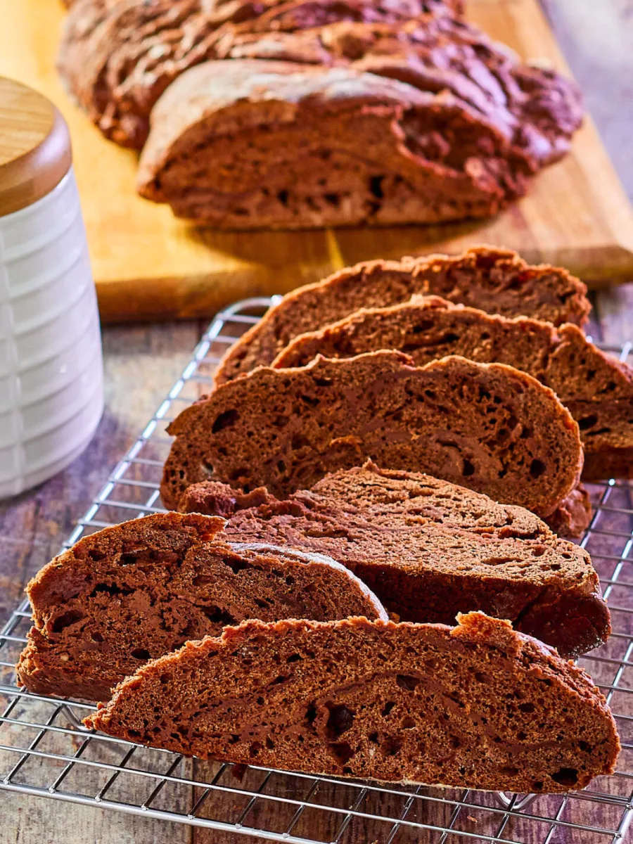 Angled view of deep chocolate bobca bread sliced on a cooling rack - Hostess At Heart