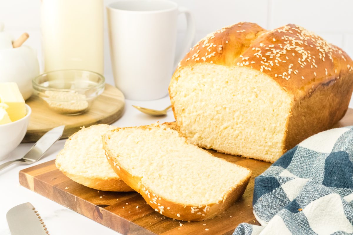 Sliced loaf of sesame bread, side view on a cutting board.