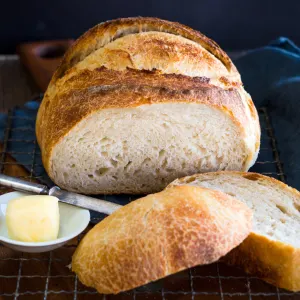 A front view of a loaf of overnight sourdough bread with the front piece sliced off showing a soft crumb with a crispy crust. Hostess At Heart