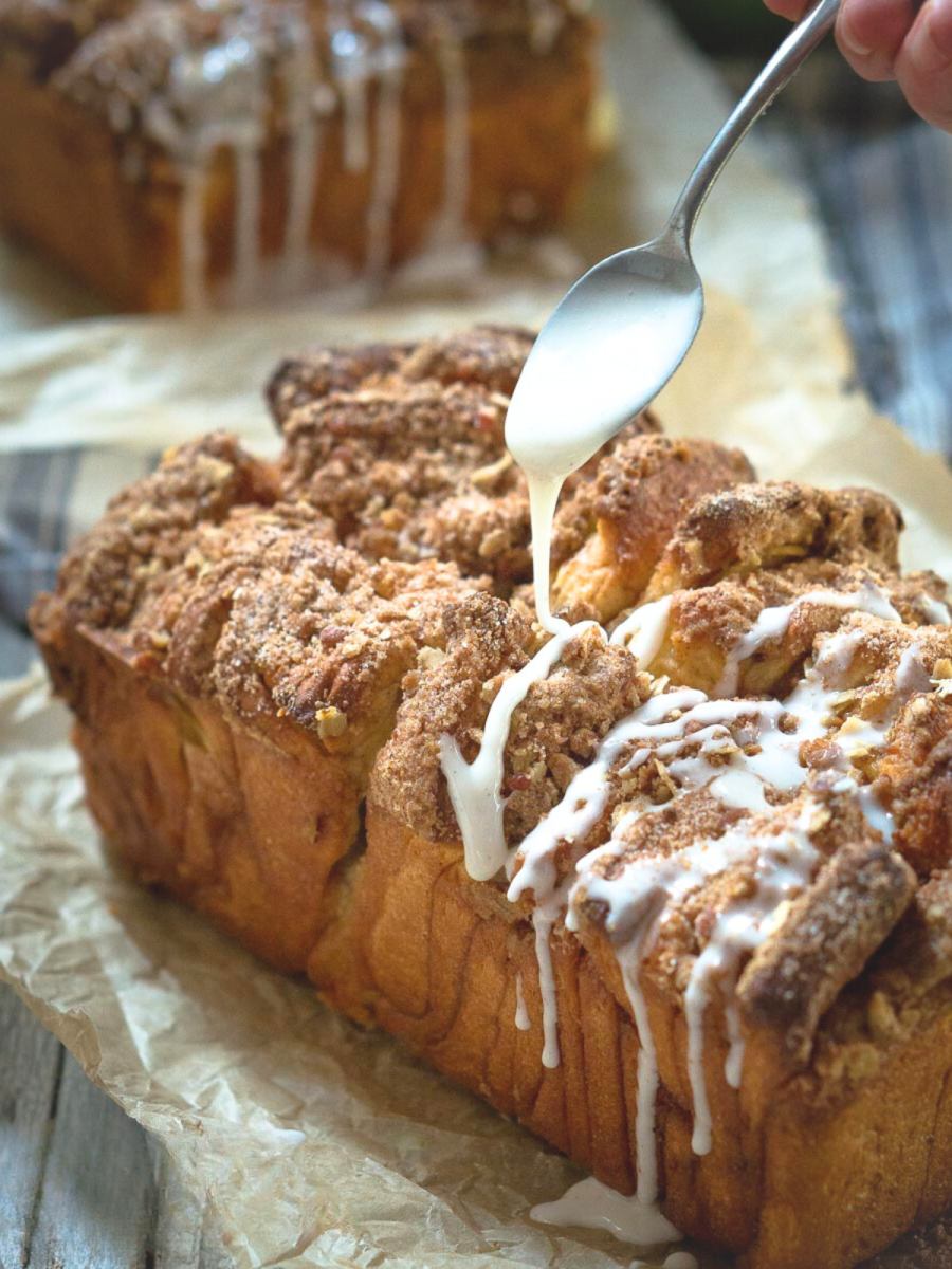 Sideview of a loaf of Apple Pull-Apart Bread covered in streusel and glaze dripping down the side - Hostess At Heart