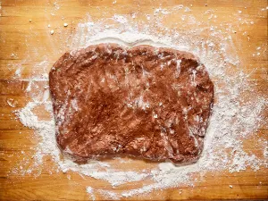 Chocolate flavored bread dough rolled into a rectangle on a floured cutting board - Hostess At Heart