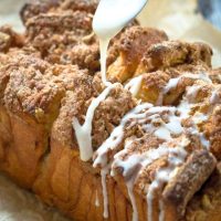 A loaf of Apple pull apart bread covered in streusel and dripping with glaze. Hostess At Heart