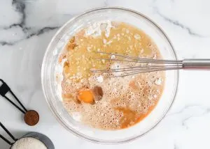 A mixing bowl filled with the wet ingredients used to make apple cider muffins. Hostess At Heart