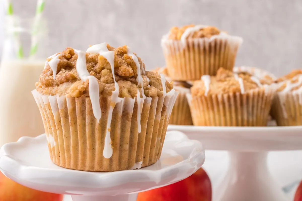 A sideview of baked Apple Muffins dripping with glaze. - Hostess At Heart