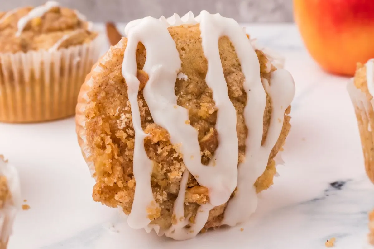 A tableview of a muffin sitting on its side showing a crumbled topping whisked with glaze. Hostess At Heart