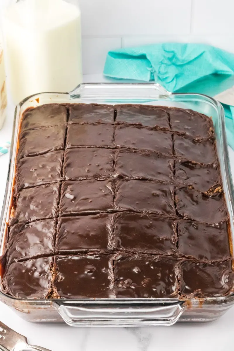 Angled view of a baking pan filled with cut pieces of chocolate brownies topped with chocolate frosting.