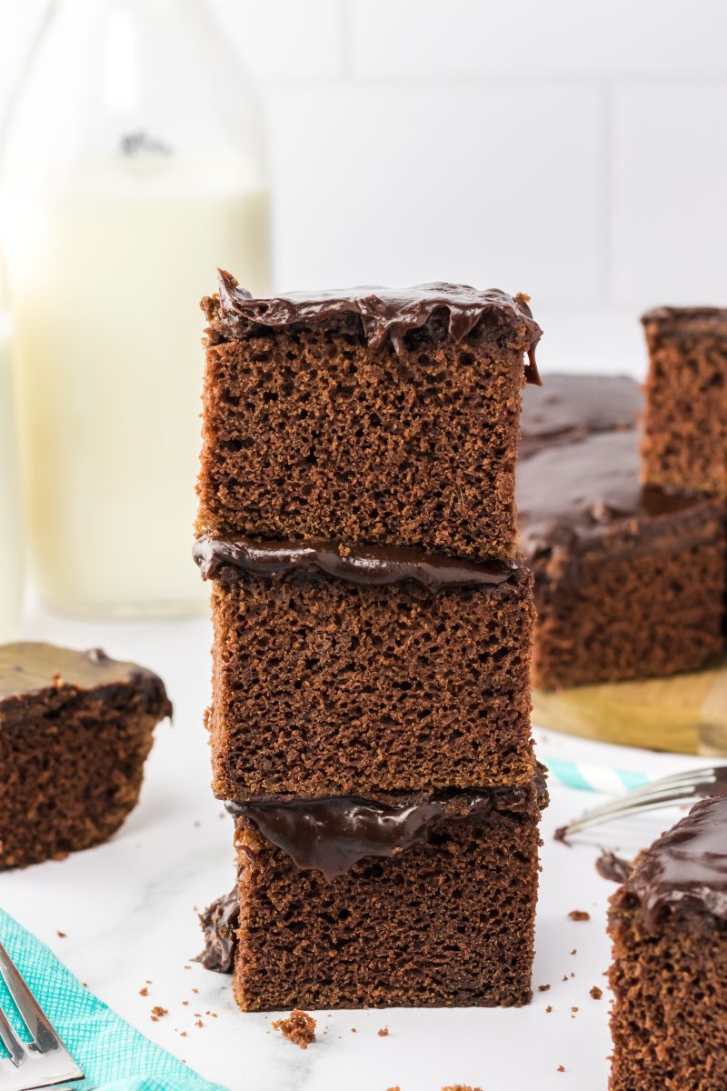 Three brownies topped with chocolate frosting stacked on each other - Hostess At Heart