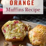 Top down image of a cut in half baked muffin dotted with cranberry and orange.